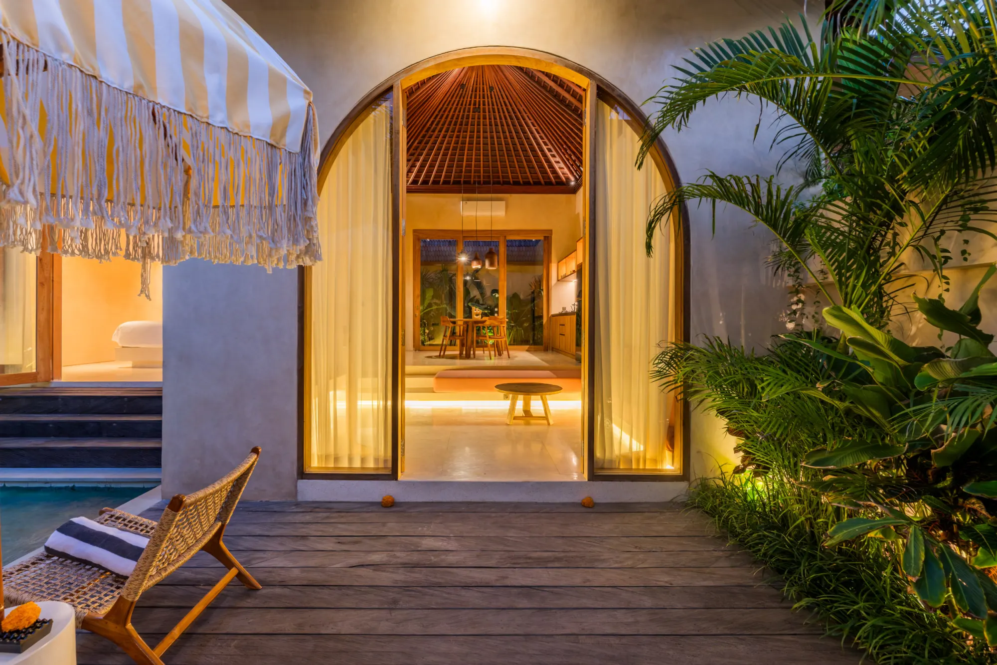 Modern villa entrance with arched glass doors and outdoor deck