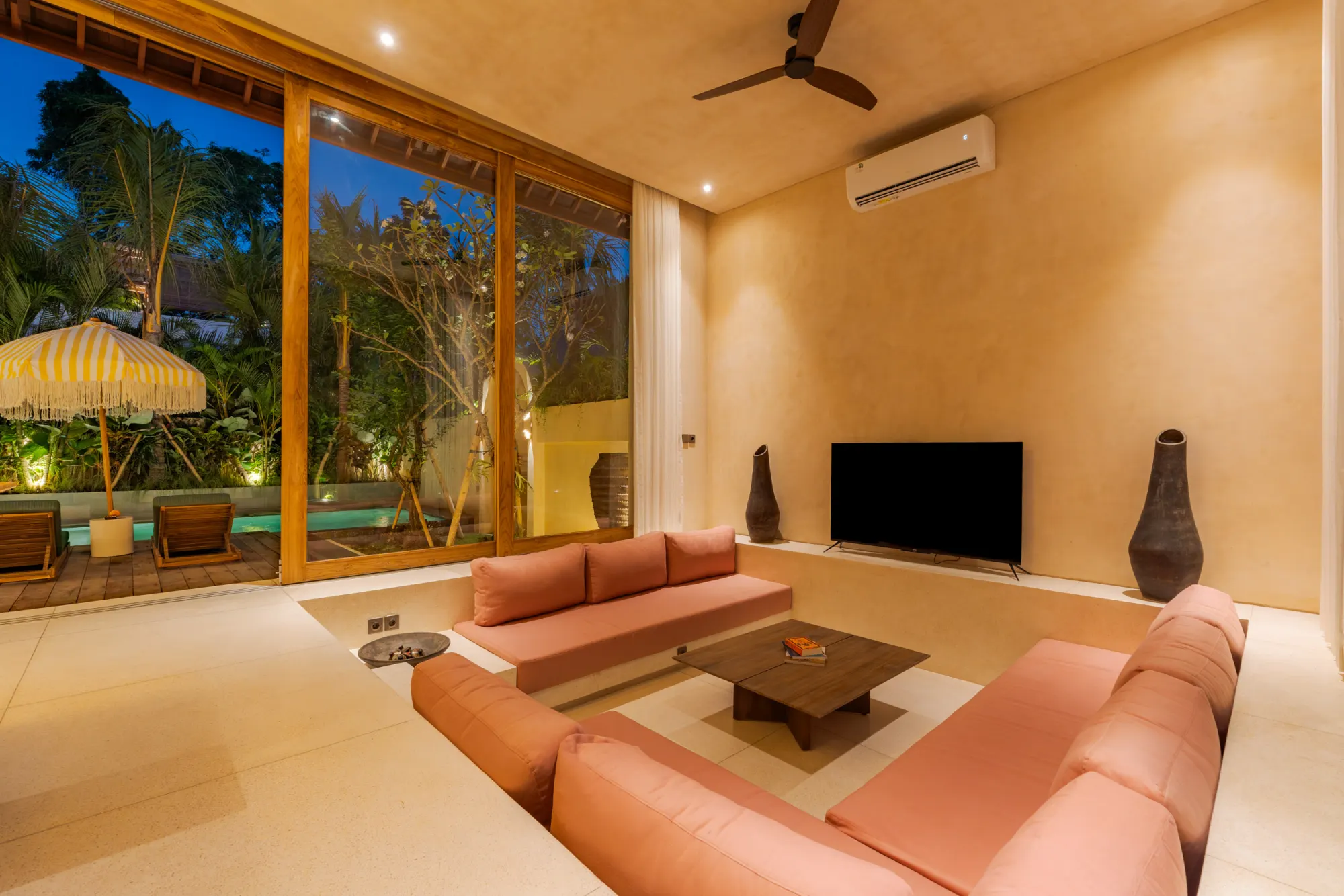 Living area with garden views and glimpse of illuminated pool