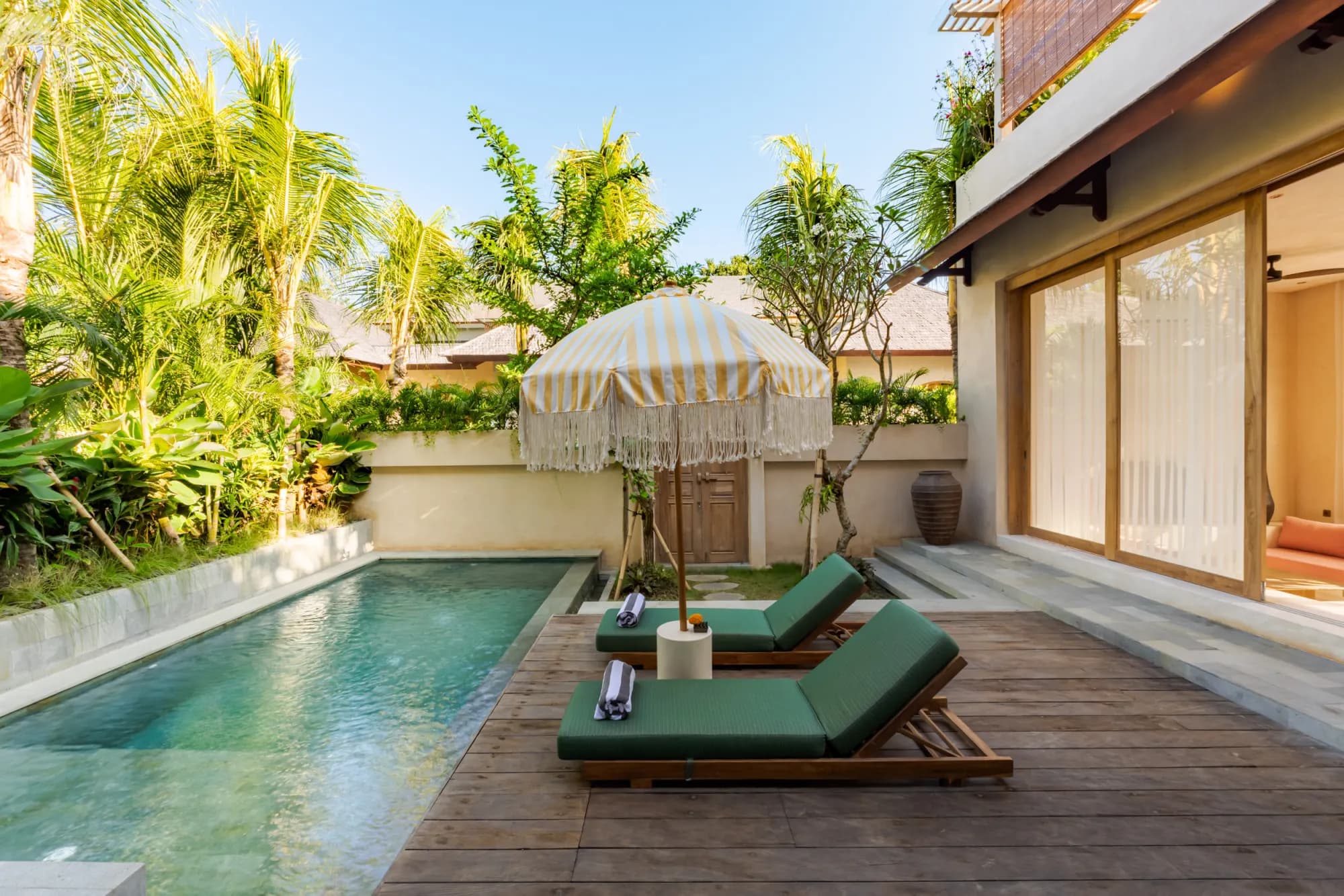 Pool with aquamarine water and loungers surrounded by palms