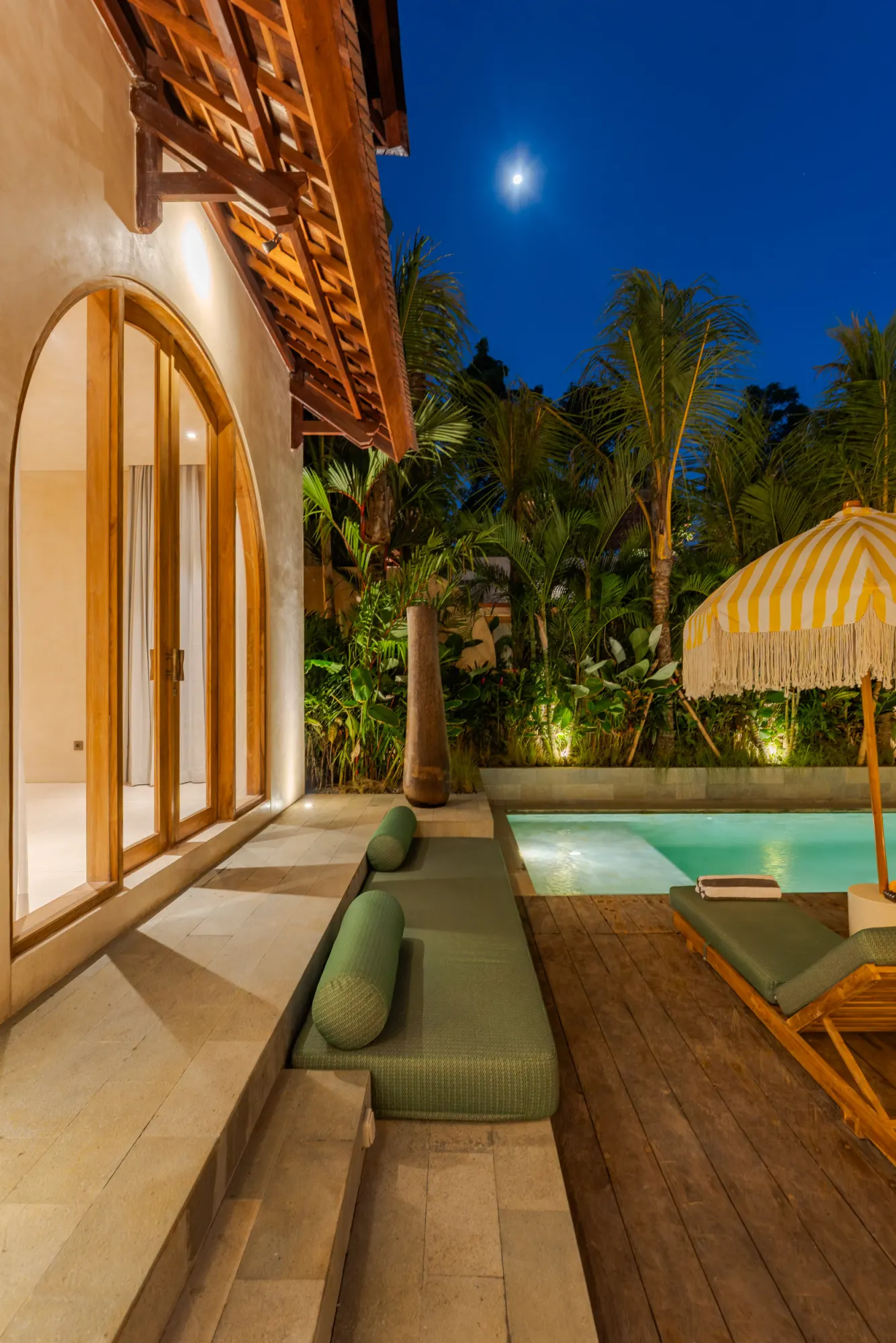 Night-lit pool with loungers and spa basin area
