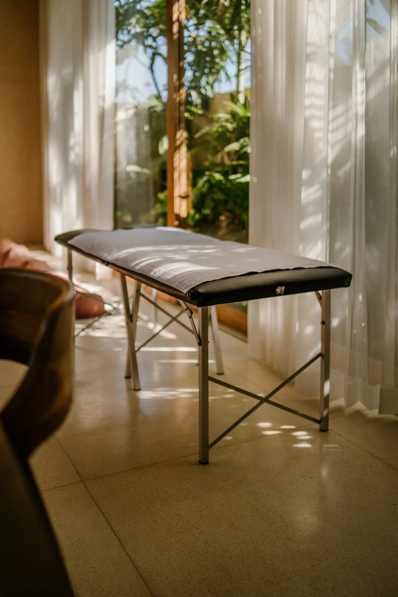 Massage bed overlooking lush garden through glass doors