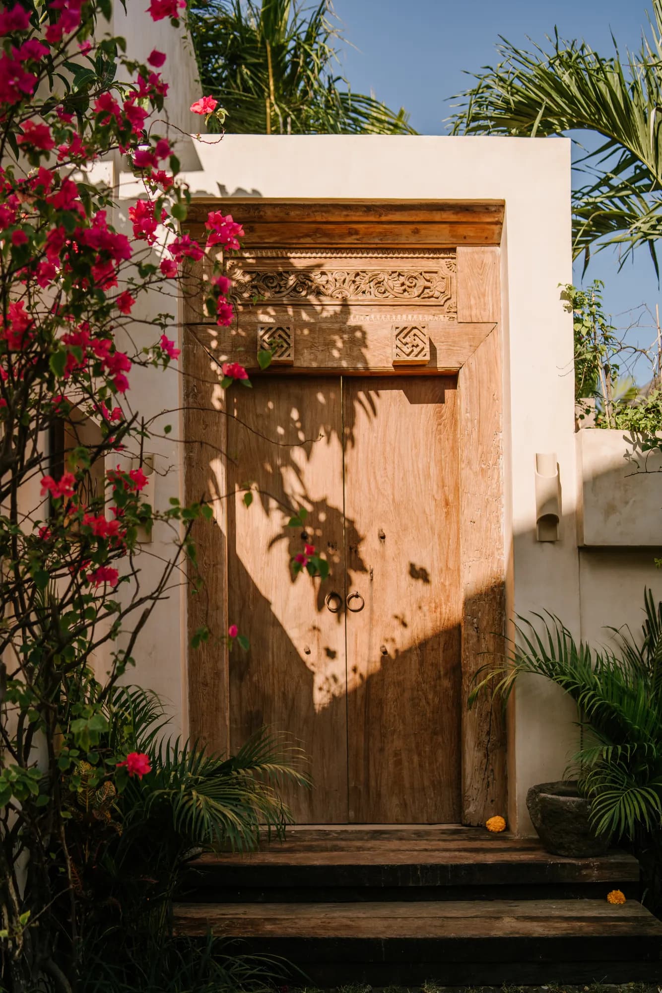 Ornate wooden door framed by vibrant magenta bougainvillea