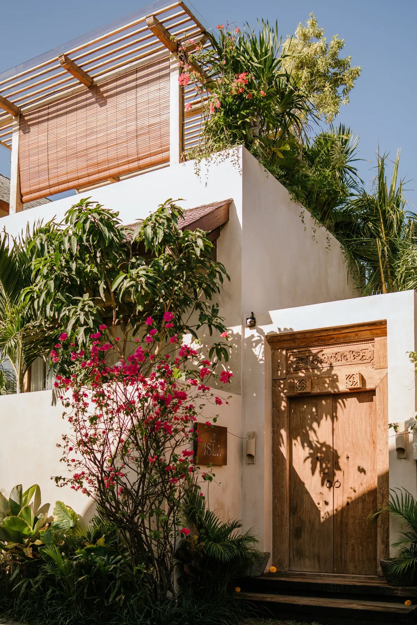 Modern villa exterior with pergola, flowers, and wooden door
