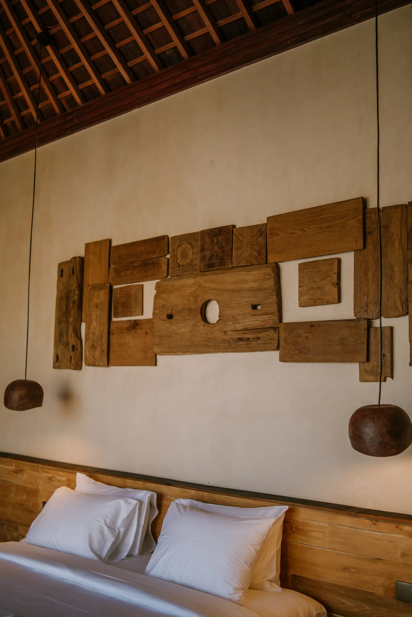 Wooden bed headpiece with sculptural carving against textured wall