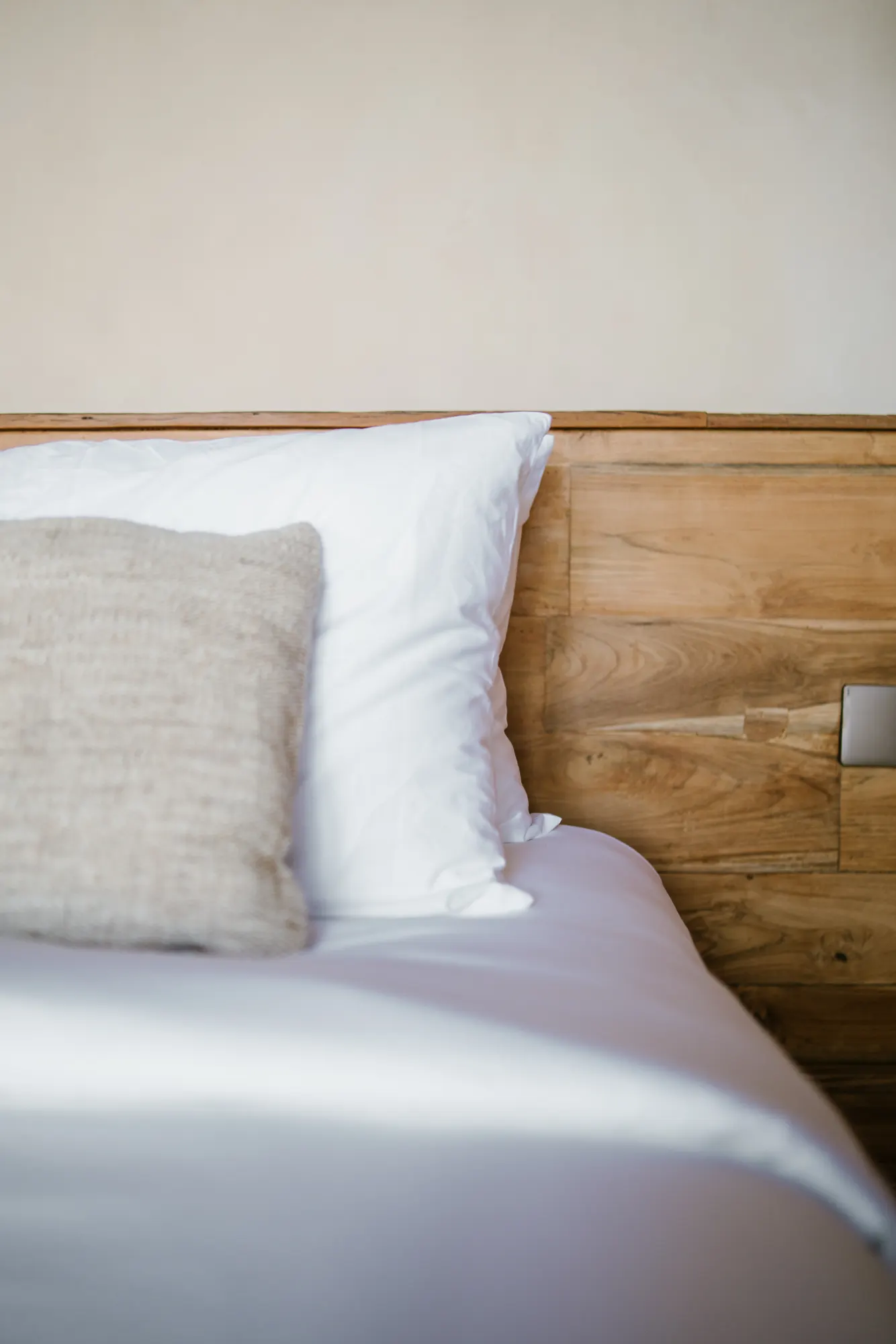 Bedroom detail with white linens and wooden frame