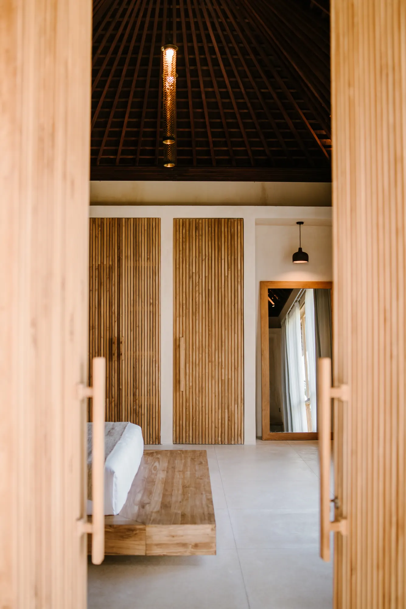 Interior hallway with geometric ceiling and pendant lighting