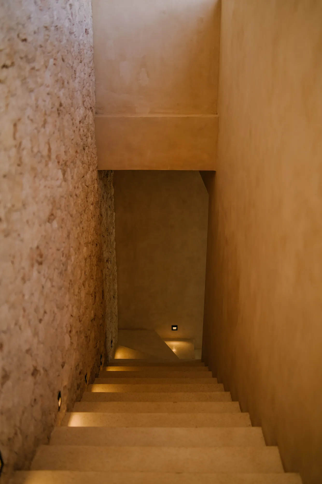 Interior staircase with textured stone walls and lighting